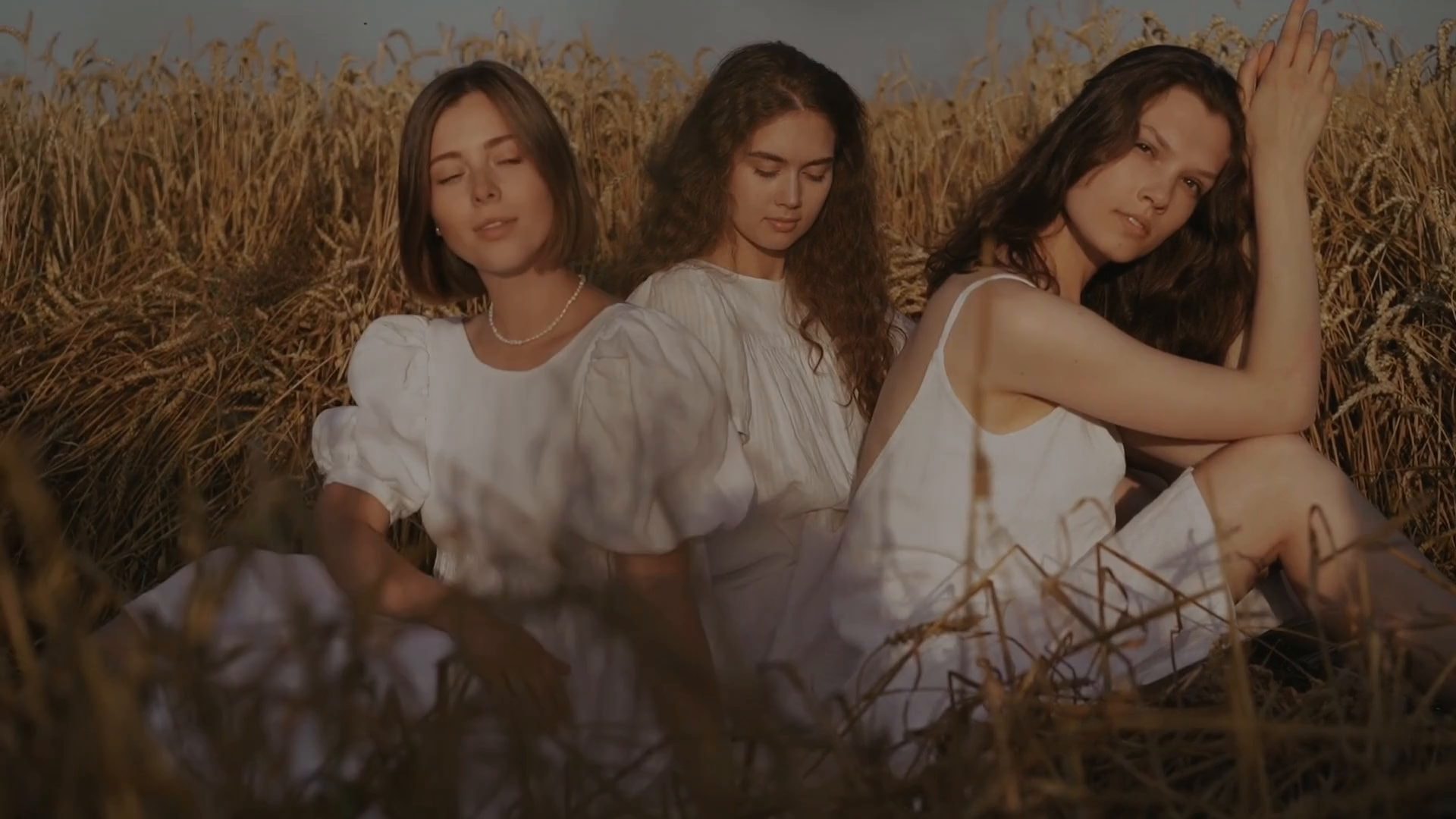 Tres mujeres sentadas juntas en un campo de trigo, en calma